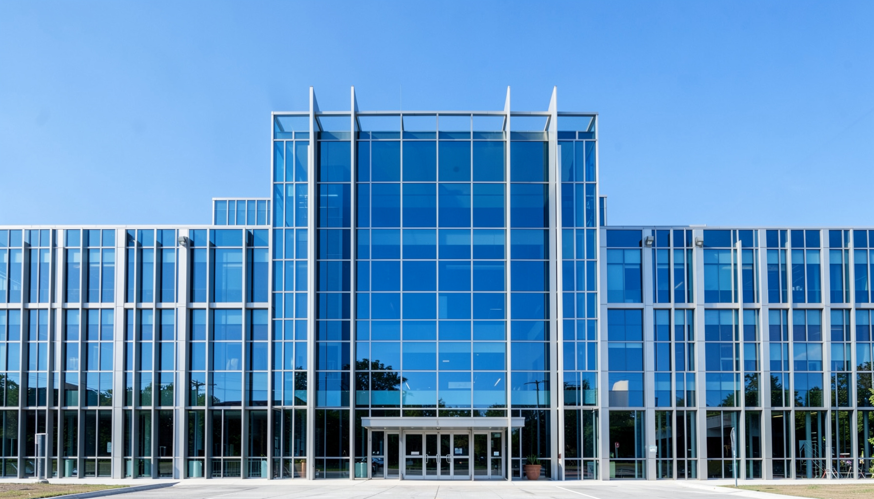 Fotografía arquitectónica simétrica de un edificio universitario moderno con fachada de cristal y acero, líneas limpias y cielo despejado, transmitiendo seriedad académica